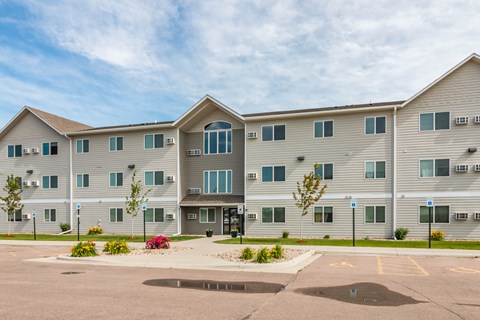 A large apartment complex with a parking lot in front.